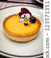 Freshly baked fruit tart topped with edible flowers and berries during an afternoon dessert display 123571351