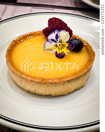 Freshly baked fruit tart topped with edible flowers and berries during an afternoon dessert display 123571351