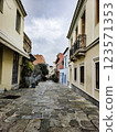 Cobblestone street in a historic neighborhood with colorful buildings and overcast sky 123571353