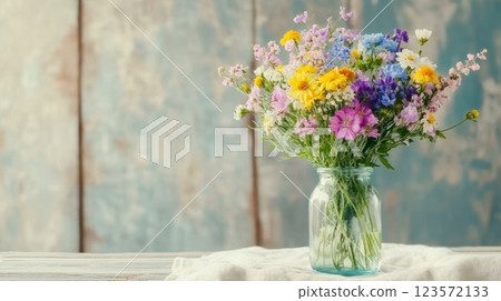 Seasonal wildflowers in a glass bottle add rustic charm to a linen cloth, capturing serenity 123572133