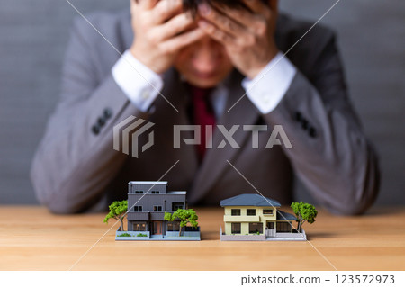A middle-aged male businessman in a suit and a house model A middle-aged male businessman in a suit and a house model 123572973