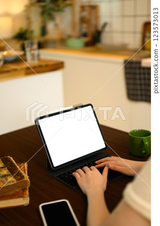 Close up of woman typing on keyboard of digital tablet at the dining table Close up of woman typing on keyboard of digital tablet at the dining table 123573013