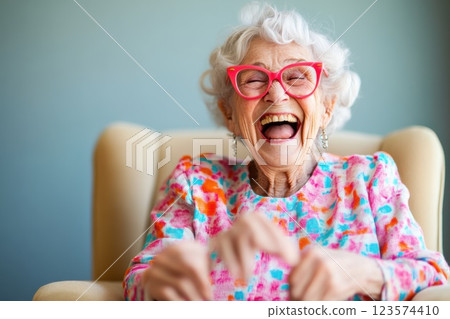 Elderly woman enjoying a joyful moment with laughter in her cozy chair 123574410
