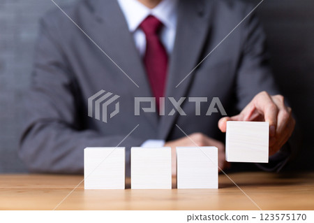 四塊白色木塊和穿著西裝的中年男性商人 四塊白色木塊和穿著西裝的中年男性商人 123575170