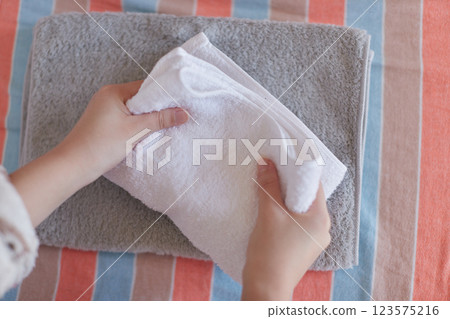 一位女士在家中臥室整理洗好的毛巾的手 123575216