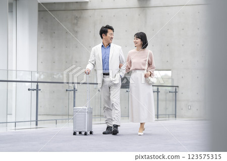 一對 50 多歲的夫婦面帶微笑，拎著包包散步 123575315