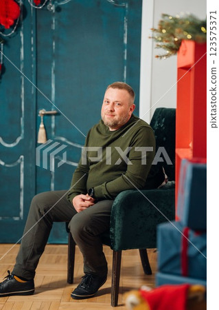 A man in an armchair against the background of a door decorated for New Year. A man in an armchair against the background of a door decorated for New Year. 123575371