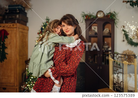 Beautiful mother and daughter at the Christmas tree. Beautiful mother and daughter at the Christmas tree. 123575389