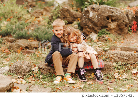 Children enjoying a cozy moment outdoors during autumn season Children enjoying a cozy moment outdoors during autumn season 123575423