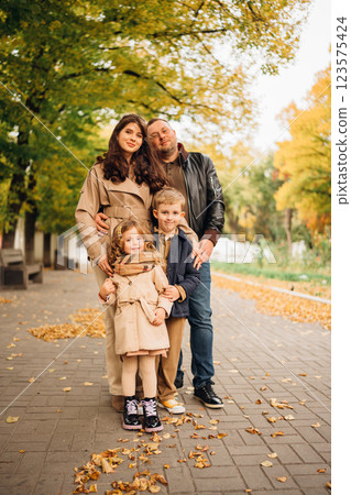 Family enjoys a leisurely stroll on a picturesque autumn day Family enjoys a leisurely stroll on a picturesque autumn day 123575424