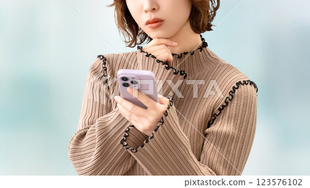 女人/女商人一邊看著智慧型手機一邊思考 女人/女商人一邊看著智慧型手機一邊思考 123576102