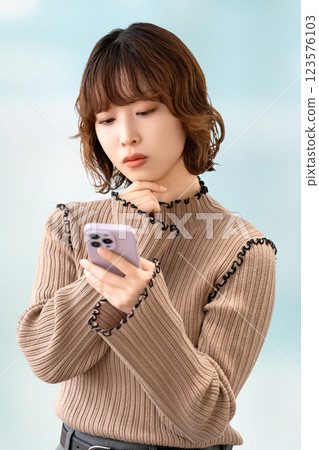 女人/女商人一邊看著智慧型手機一邊思考 女人/女商人一邊看著智慧型手機一邊思考 123576103