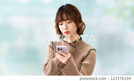 女人/女商人一邊看著智慧型手機一邊思考 女人/女商人一邊看著智慧型手機一邊思考 123576104