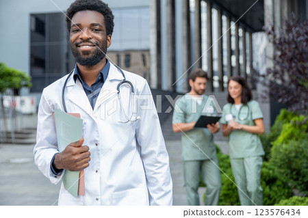 Good-looking young dark-skinned doctor in a lab coat looking confident. Good-looking young dark-skinned doctor in a lab coat looking confident. 123576434