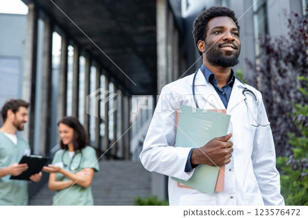 Good-looking young dark-skinned doctor in a lab coat looking confident. Good-looking young dark-skinned doctor in a lab coat looking confident. 123576472