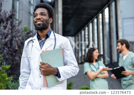 Good-looking young dark-skinned doctor in a lab coat looking confident. 123576473