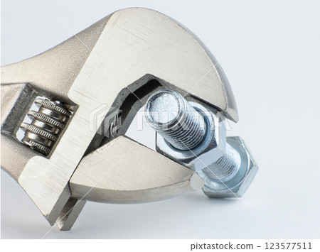 A wrench securely grips a metal bolt and nut for adjustment 123577511