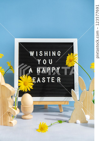 WISHING YOU A HAPPY EASTER text on letter board with bunny wooden figures and fresh flowers. Easter composition content still life. Christian symbols of spring WISHING YOU A HAPPY EASTER text on letter board with bunny wooden figures and fresh flowers. Easter composition content still life. Christian symbols of spring 123577691