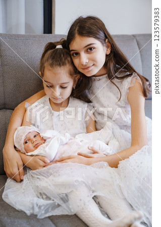Newborn baby in the arms of his sisters in a white dress Newborn baby in the arms of his sisters in a white dress 123579383