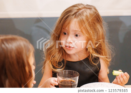 Beautiful little girl eating and drinking soda. 123579385