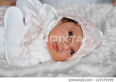 Newborn baby in a hat with pink lace on the bed in the bedroom 123579399