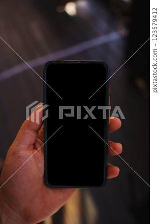 A smartphone in a man's hand with a blank black screen.  123579412