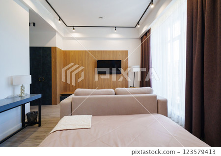 A cozy living room with large windows covered by brown curtains.  123579413