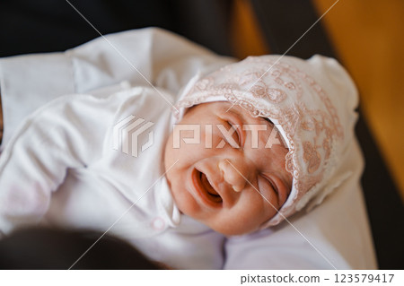 Newborn baby in a hat with pink lace crying in arms 123579417