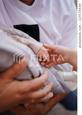 A child's hand holds a small baby's hand.  123579449