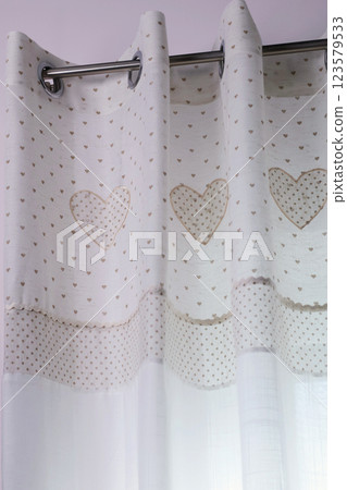 Vintage white curtains on metal rings on natural material with embroidered hearts at home. Cleaning and cleanliness. Interior and textiles. Vintage white curtains on metal rings on natural material with embroidered hearts at home. Cleaning and cleanliness. Interior and textiles. 123579533
