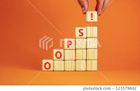Oops symbol. Concept word Oops on beautiful wooden blocks. Beautiful orange table orange background. Businessman hand. Business lifestyle oops concept. Copy space. 123579692
