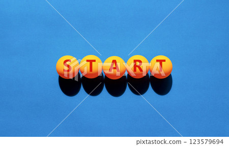 Start symbol. Concept word Start on beautiful yellow tennis ping pong balls. Beautiful wooden table wooden background. Business lifestyle start concept. Copy space. Start symbol. Concept word Start on beautiful yellow tennis ping pong balls. Beautiful wooden table wooden background. Business lifestyle start concept. Copy space. 123579694