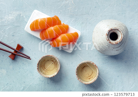 Sake and ochoko, traditional cup, with salmon sashimi and chopstick Sake and ochoko, traditional cup, with salmon sashimi and chopstick 123579713