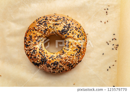 Bagel with sesame seeds, overhead flat lay shot on baking paper 123579770