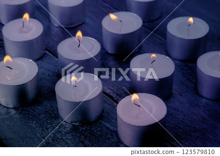 Tea light candles on a dark background, many lights in the dark 123579810