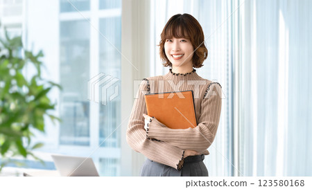 Smiling woman/businesswoman holding a binder 123580168