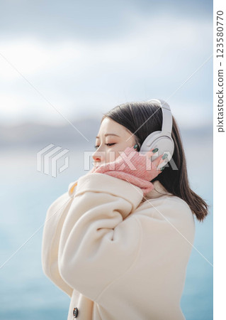 Young woman listening to music with headphones on the beach 123580770