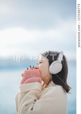Young woman listening to music with headphones on the beach Young woman listening to music with headphones on the beach 123580774