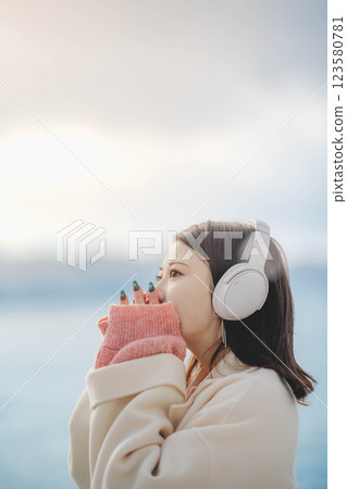 Young woman listening to music with headphones on the beach Young woman listening to music with headphones on the beach 123580781