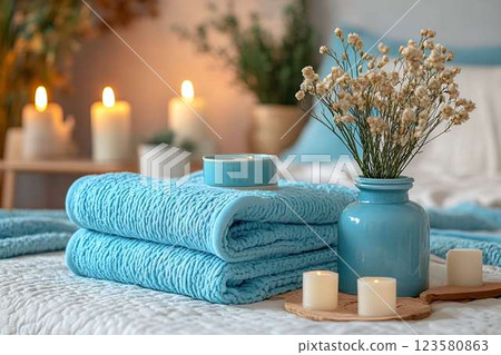 Spa-like bedroom with blue towels, candles, and dried flowers 123580863