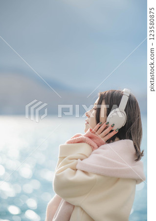 湖邊戴著耳機聽音樂的年輕女子 123580875