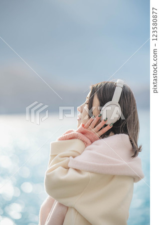 Young woman listening to music on headphones by the lake Young woman listening to music on headphones by the lake 123580877