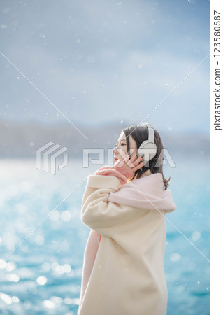 湖邊戴著耳機聽音樂的年輕女子 湖邊戴著耳機聽音樂的年輕女子 123580887