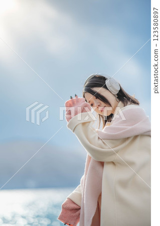 湖邊戴著耳機聽音樂的年輕女子 湖邊戴著耳機聽音樂的年輕女子 123580897