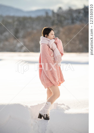 在溫暖的冬日陽光下，身穿針織服裝的年輕女子 123580910
