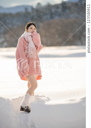 在溫暖的冬日陽光下，身穿針織服裝的年輕女子 123580911