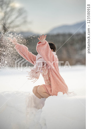 在溫暖的冬日陽光下,身穿針織服裝的年輕女子 在溫暖的冬日陽光下,身穿針織服裝的年輕女子 123580918