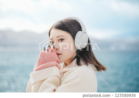 Young woman listening to music on headphones by the lake 123580930