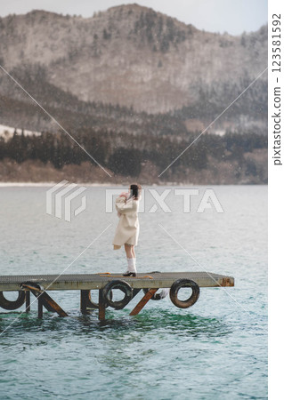 Young woman standing on a pier on a lake 123581592