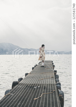 Young woman standing on a pier on a winter lake 123581740
